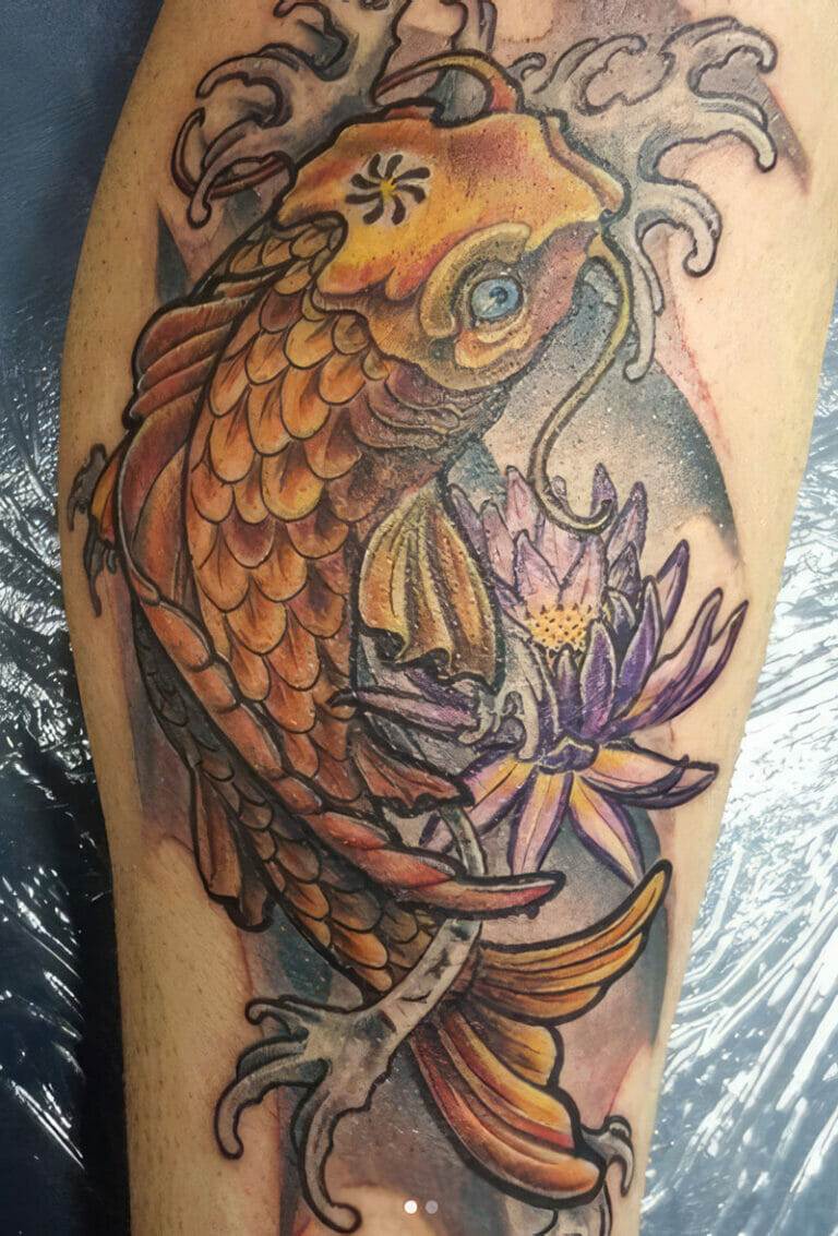 A detailed tattoo of an orange koi fish intertwined with a purple lotus flower, displayed on a person's skin.