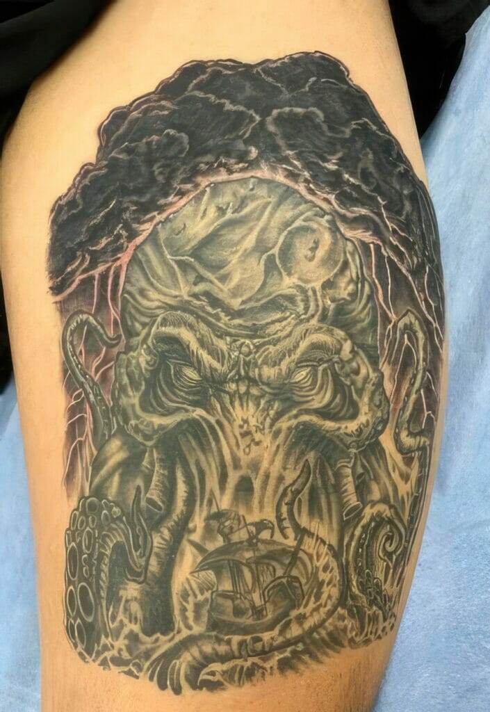 A detailed tattoo of an octopus-like creature with a ship at the bottom and dark clouds above, located on an individual's upper thigh.