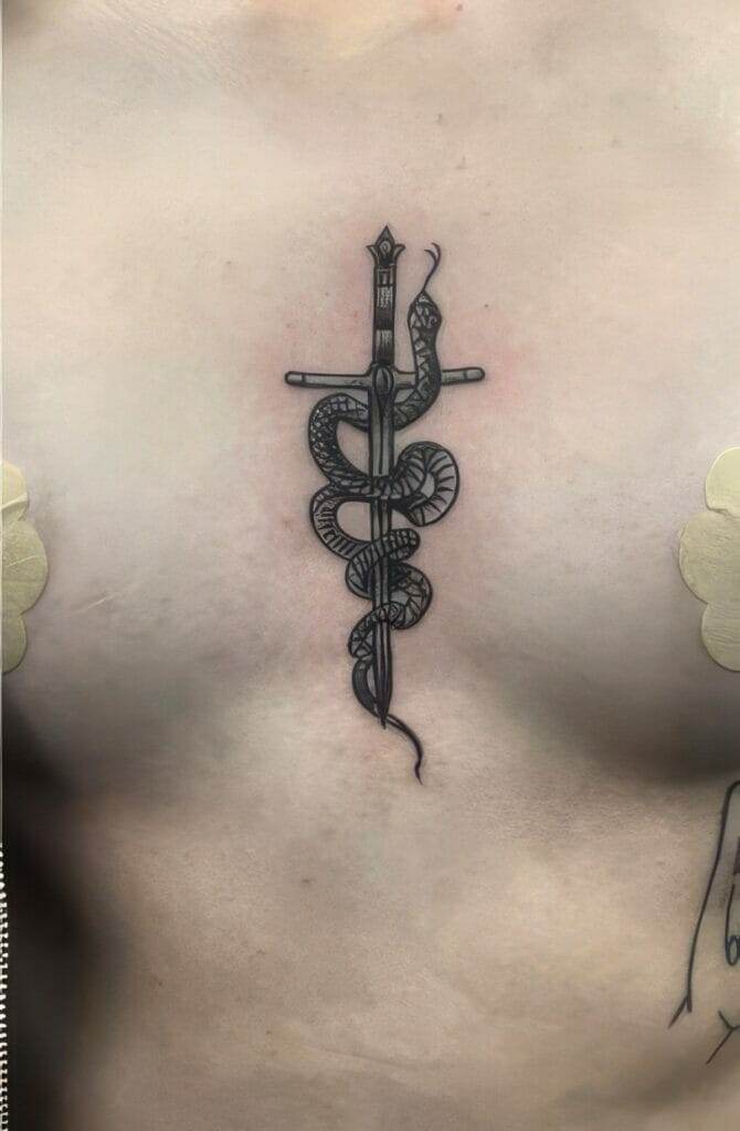 Black ink tattoo on a person's chest depicting a sword with a snake coiled around it.