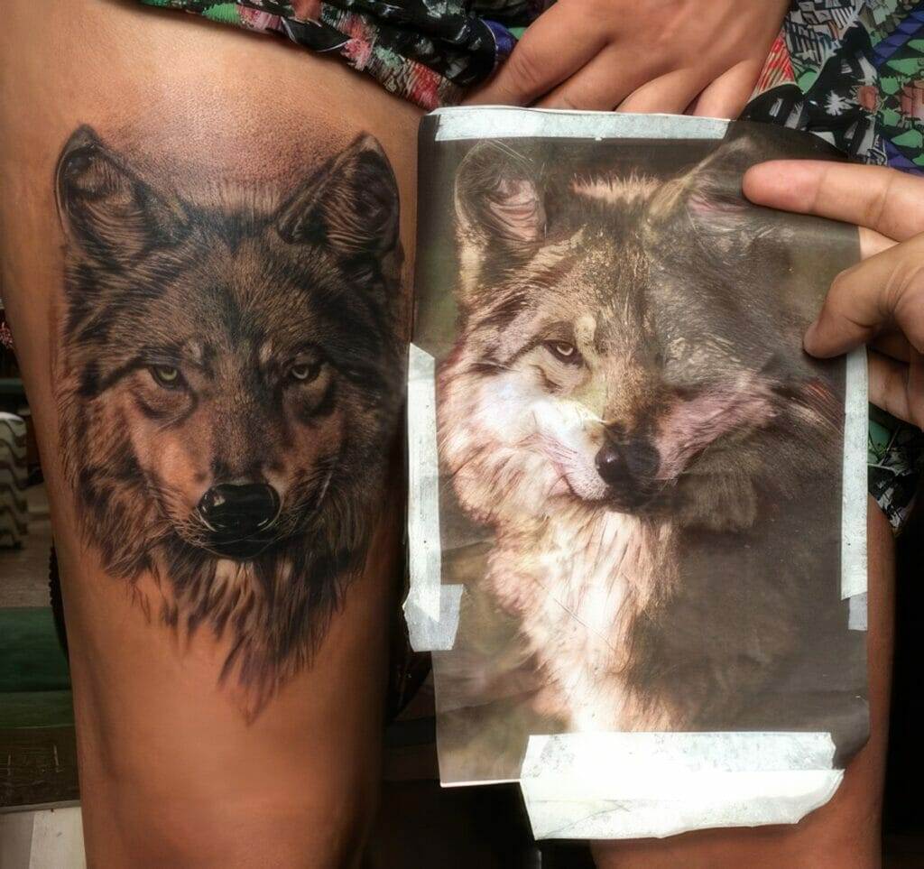 A realistic tattoo of a wolf's face on a person's thigh is shown next to a photo of a wolf that the tattoo is based on.