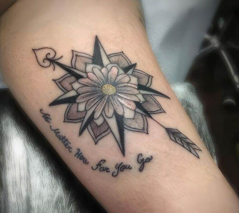 A tattoo featuring a compass with a flower in the center, an arrow, and cursive text reading "No Matter How Far You Go" on a person's skin.