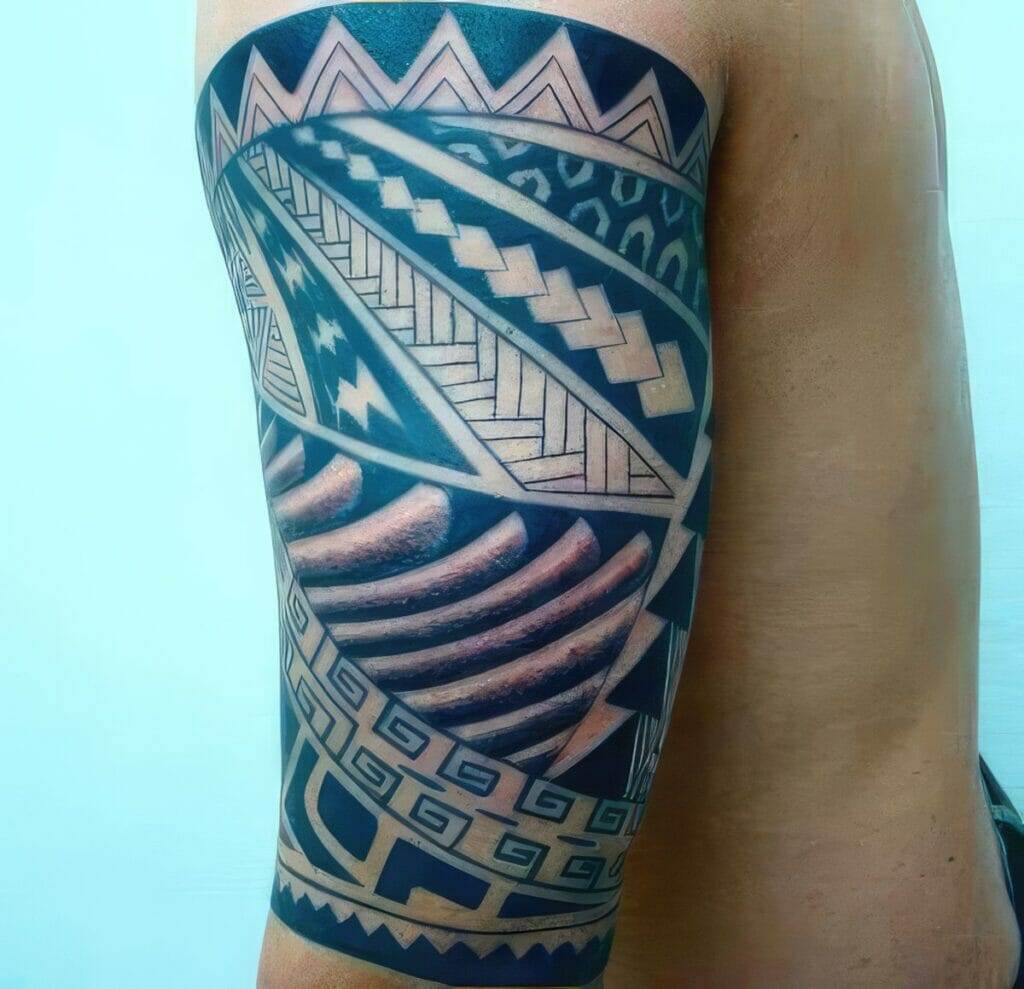 An upper arm tattoo featuring intricate geometric and tribal patterns in bold black ink with symmetrical designs.