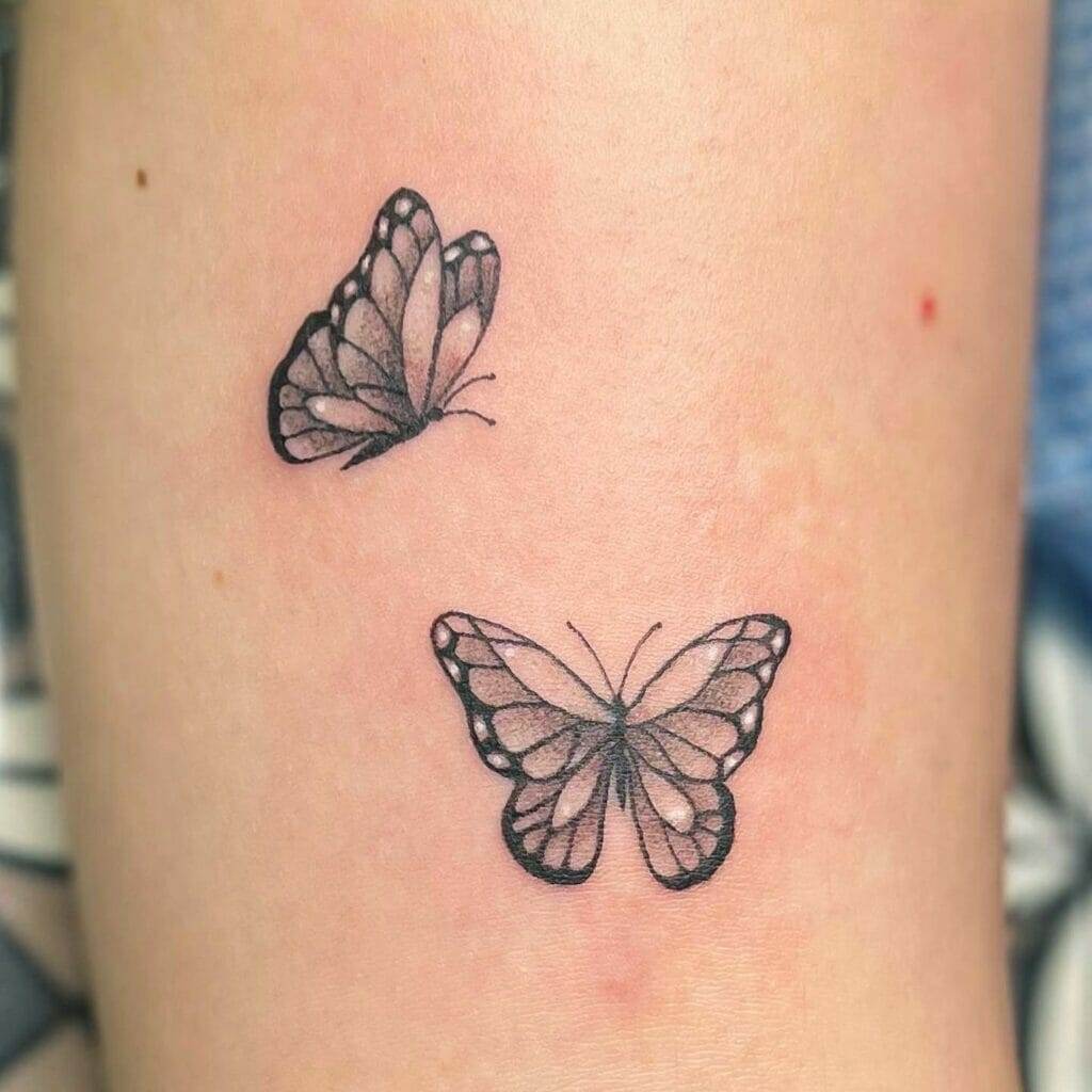 A tattoo of two black and white butterflies is inked on a person's skin. The butterflies have detailed wing patterns.