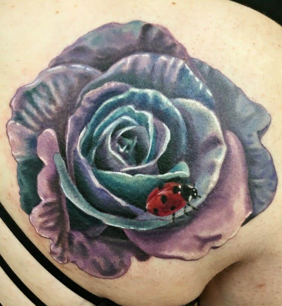 Tattoo of a purple rose with a red and black ladybug on a person's shoulder.