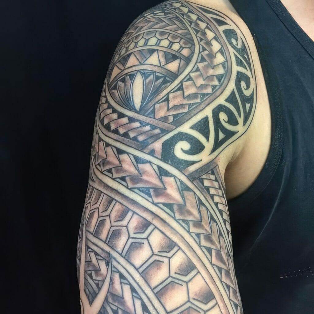 A detailed black and gray tribal sleeve tattoo covering the upper arm and shoulder of a person wearing a sleeveless black shirt.