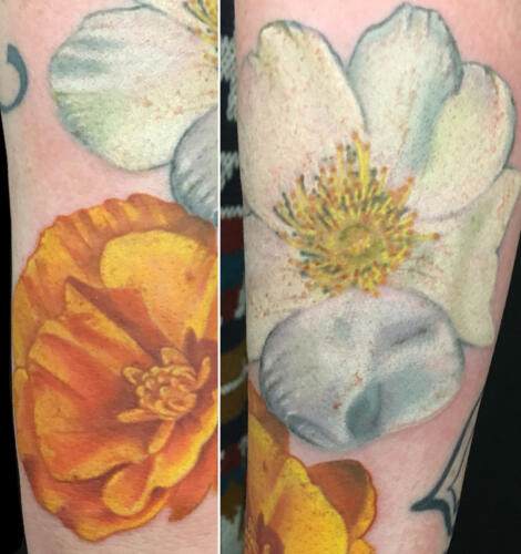Close-up of floral tattoos on a person’s arm, featuring a vibrant yellow-orange flower on one side and a white flower with a yellow center on the other side.