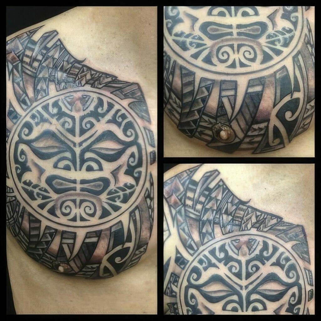 Close-up of a person's chest with a large, intricate tribal tattoo covering the shoulder and upper chest area. The tattoo includes bold, abstract shapes and symmetrical patterns.