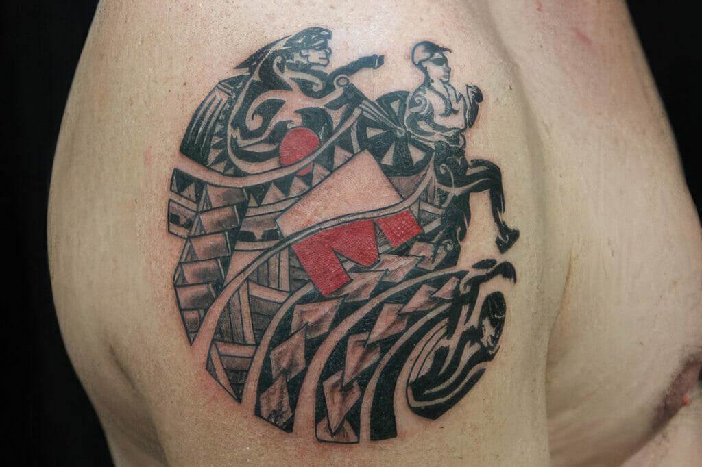 A tattoo depicting abstract figures and designs, including a runner, a wrestler, and geometric patterns, on a person's back.