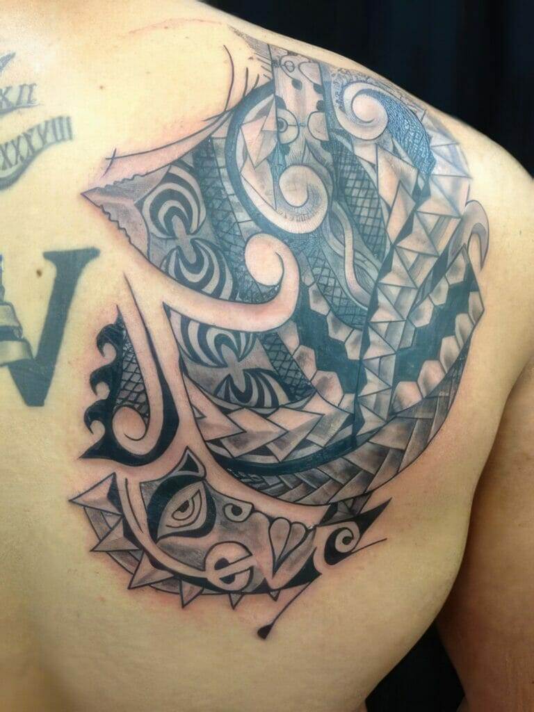 Intricate tribal-style tattoo covering the upper back and shoulder, featuring geometric patterns, swirls, and shaded elements.