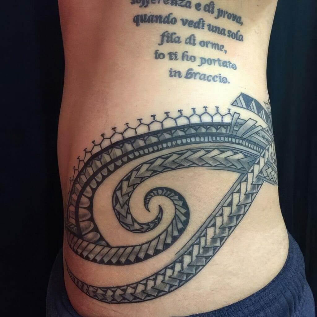 A person's side with a large tribal tattoo design. Above the tattoo, there is text in a foreign language written on the skin.