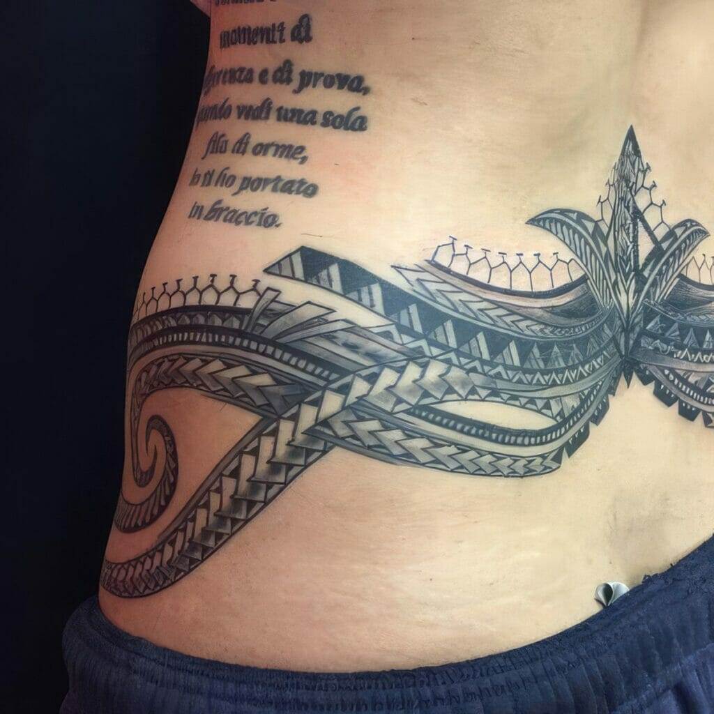 A detailed black tattoo featuring abstract geometric patterns and a script in Italian on a person's lower back.