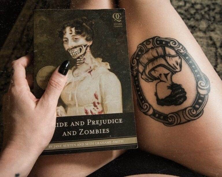 A person with black nail polish holds a book titled "Pride and Prejudice and Zombies." Their tattoo of a mushroom is visible on their thigh.