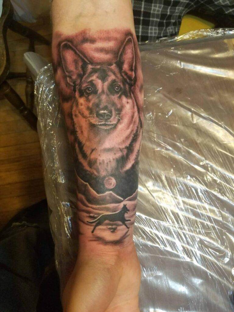 A forearm tattoo depicting a realistic German Shepherd's face with a smaller silhouette of a running dog and a moon below.