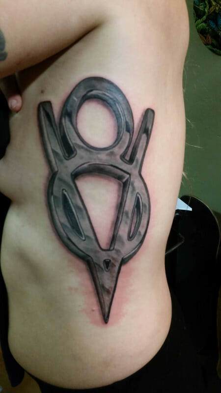 Large, stylized tattoo of a Vy symbol on a person's side torso. It features bold, interconnected lines with shades of black and gray.