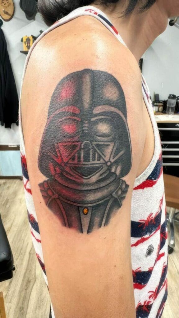 A person with a detailed Darth Vader tattoo on their upper arm. They are wearing a sleeveless shirt with a red, white, and blue pattern.