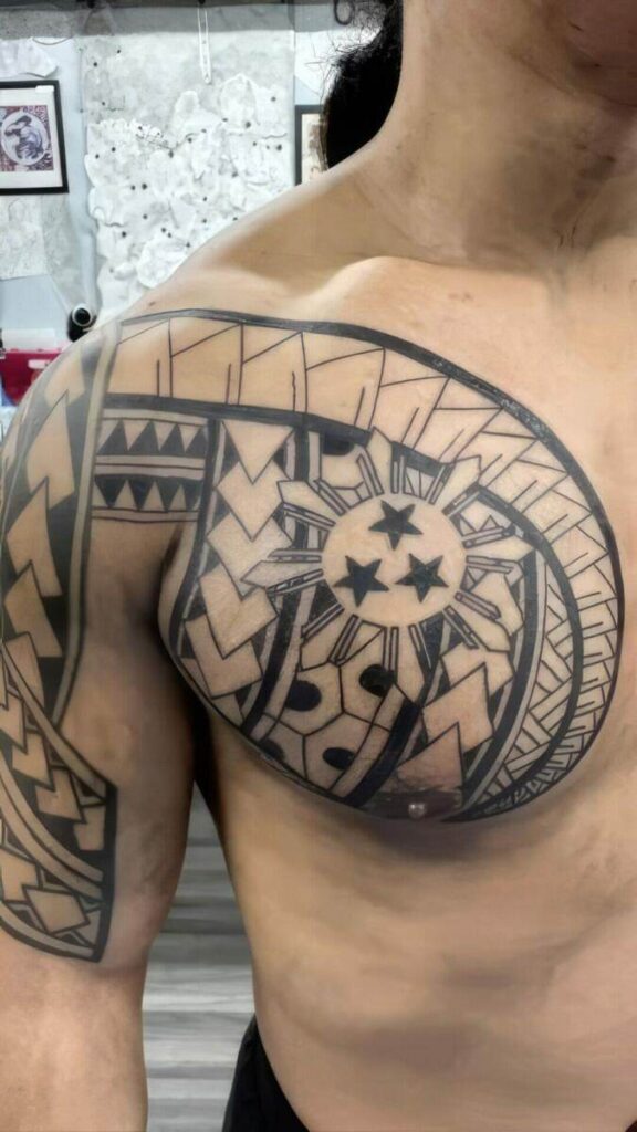 A person with a large, intricate tattoo featuring stars, geometric patterns, and tribal designs across their chest and shoulder.