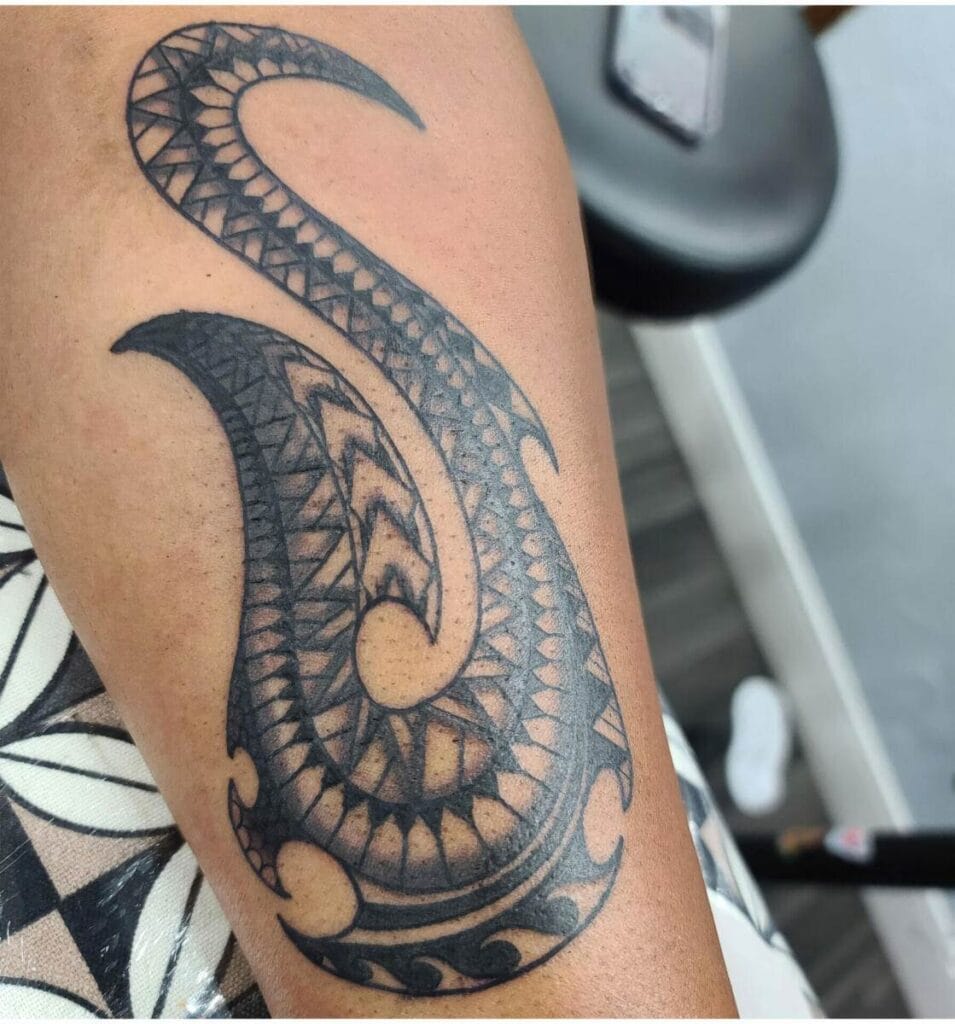 Intricate black tribal tattoo with geometric patterns and curved lines on an arm.