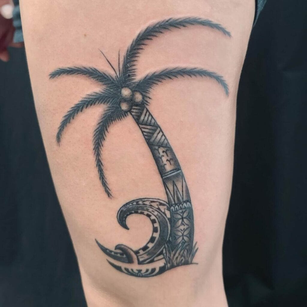 A tattoo of a palm tree with Polynesian-style patterns on the trunk, located on a person's upper arm.