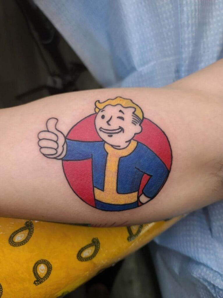 A forearm displaying a tattoo of a character with blond hair giving a thumbs-up, set against a red circular background.