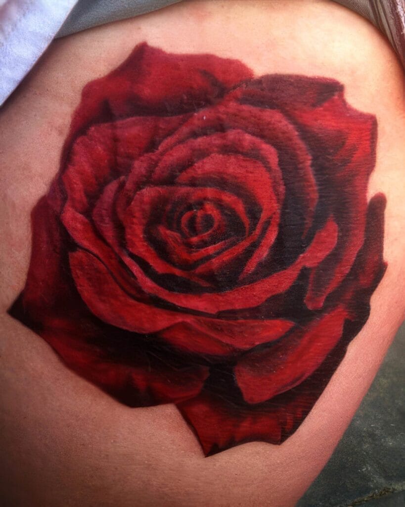 A red rose tattoo is inked on the skin, displaying detailed petals and shading.