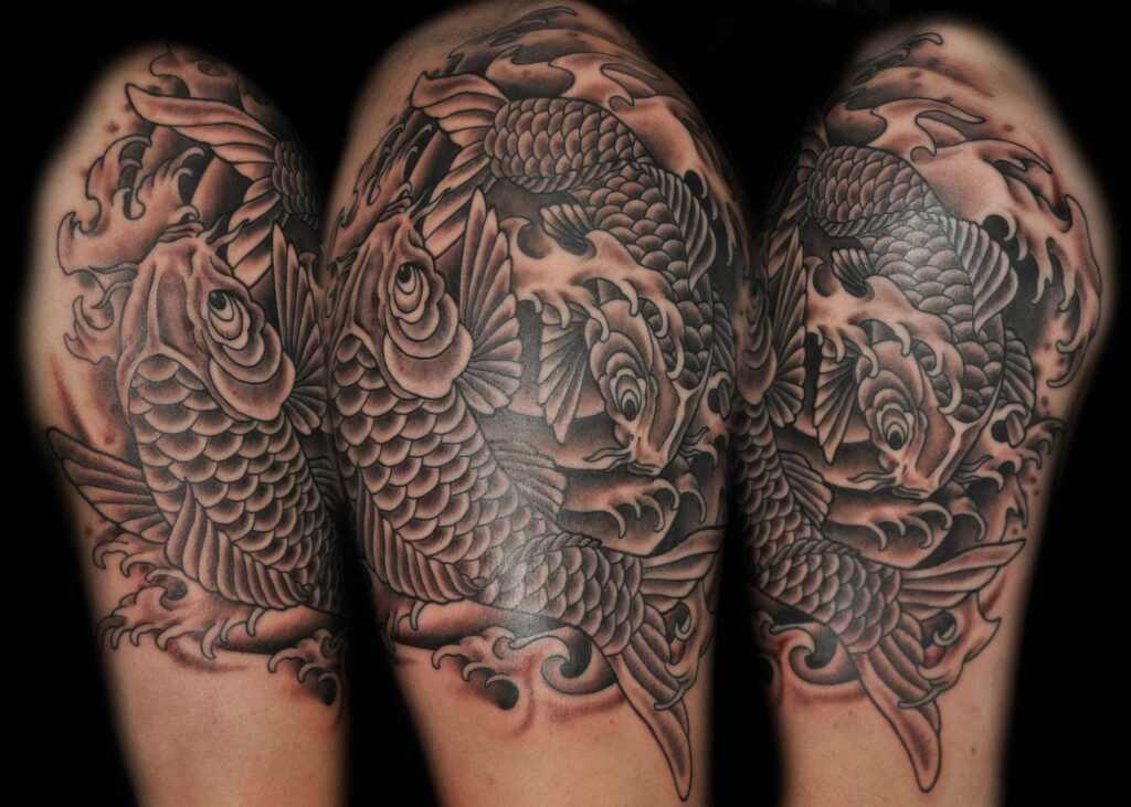 A detailed black and grey tattoo of koi fish, covering a person's shoulder and upper arm, featuring intricate scales and waves.