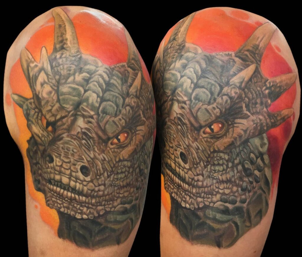 Close-up of a detailed dragon head tattoo on a person's arm, featuring scales, horns, and an orange background.