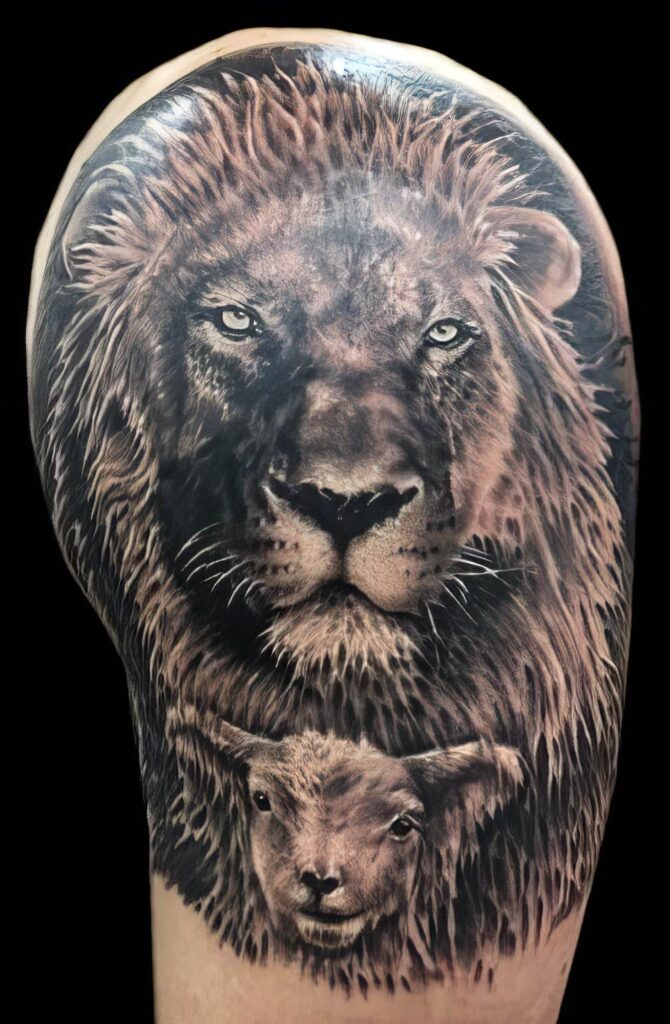 Detailed grayscale tattoo of a lion's head with a lamb's head below it, on a person's upper arm.