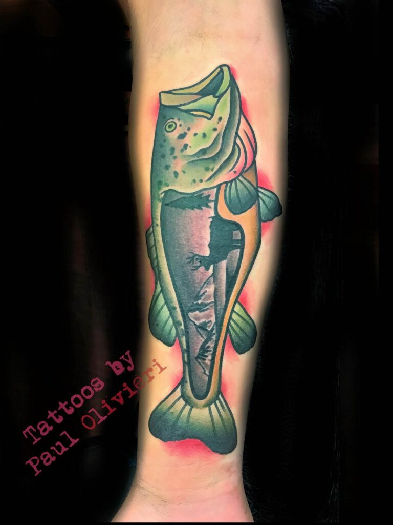 A tattoo on a person's forearm depicting a colorful fish with the text "Tattoos by Paul Olivieri" in the lower left corner.