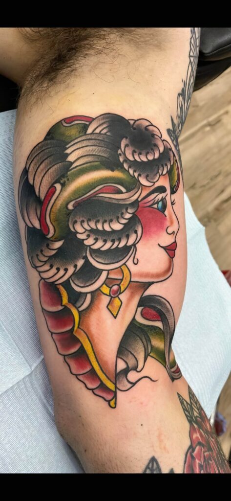 A colorful tattoo of a woman's profile with detailed hair and jewelry is on a person's arm.