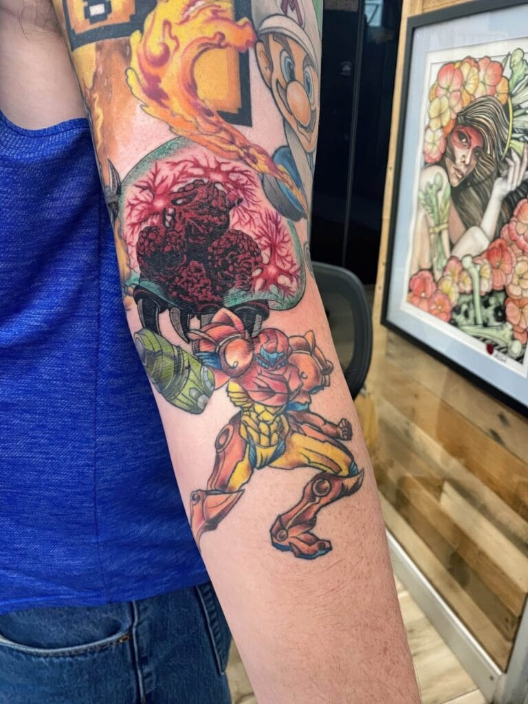 Forearm tattoo featuring various colorful designs, including video game characters and abstract elements.