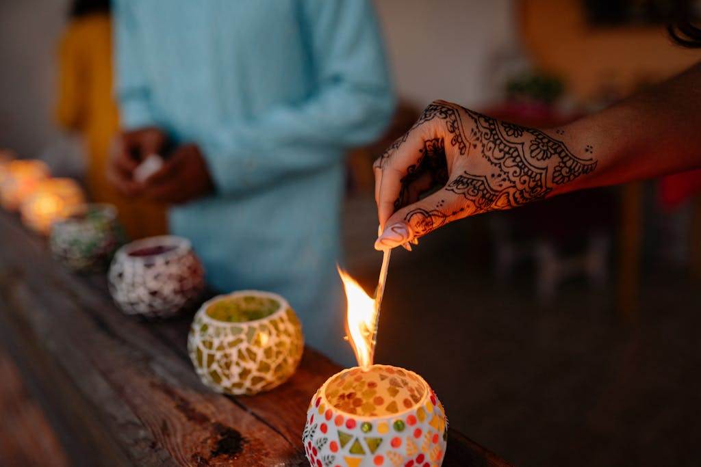 A Hand Lighting a Candle on Brown Wooden Surface