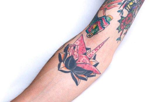 Tattoo of a pink origami crane with black outlines on a person's forearm.
