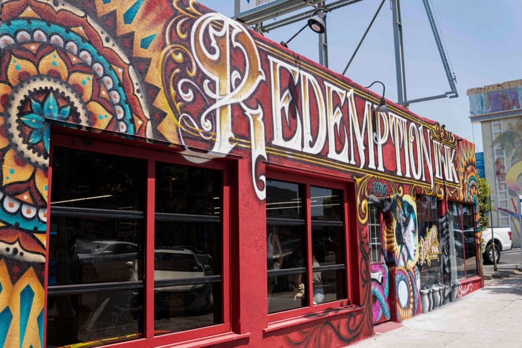 A vibrant mural on a building facade features the words "Redemption Ink" with intricate, colorful designs.