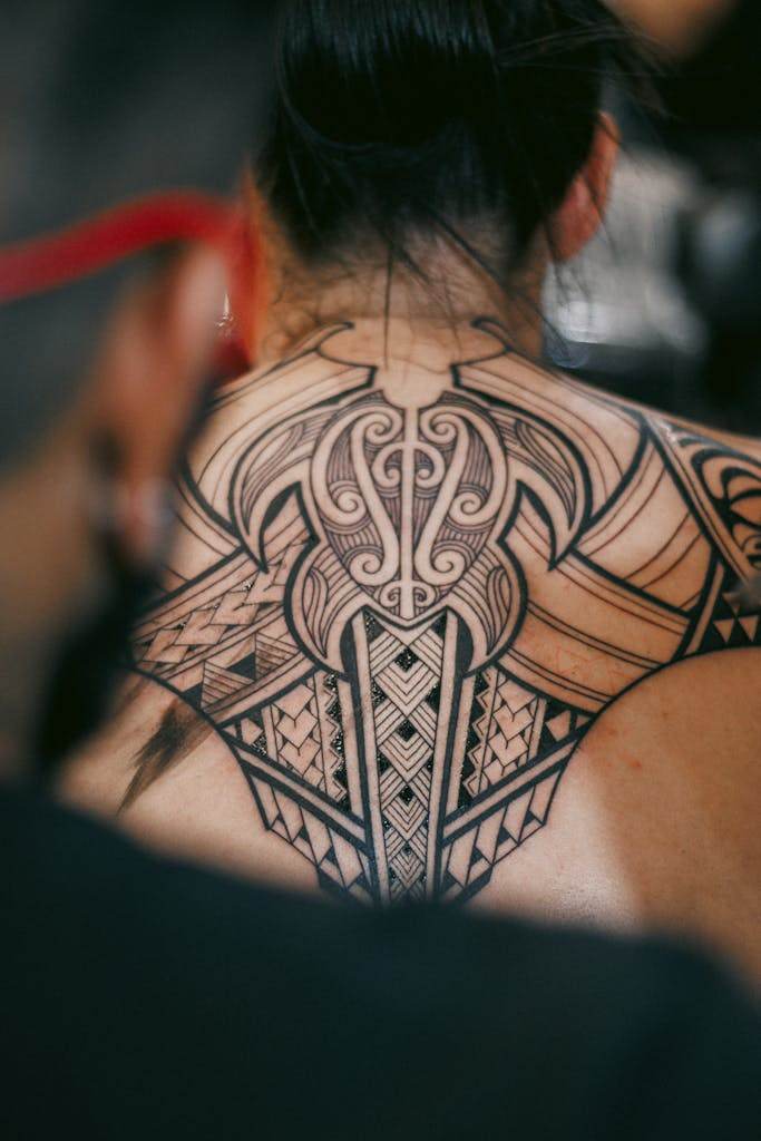 Detailed black ink tribal tattoo on a person's back, showcasing artistry.