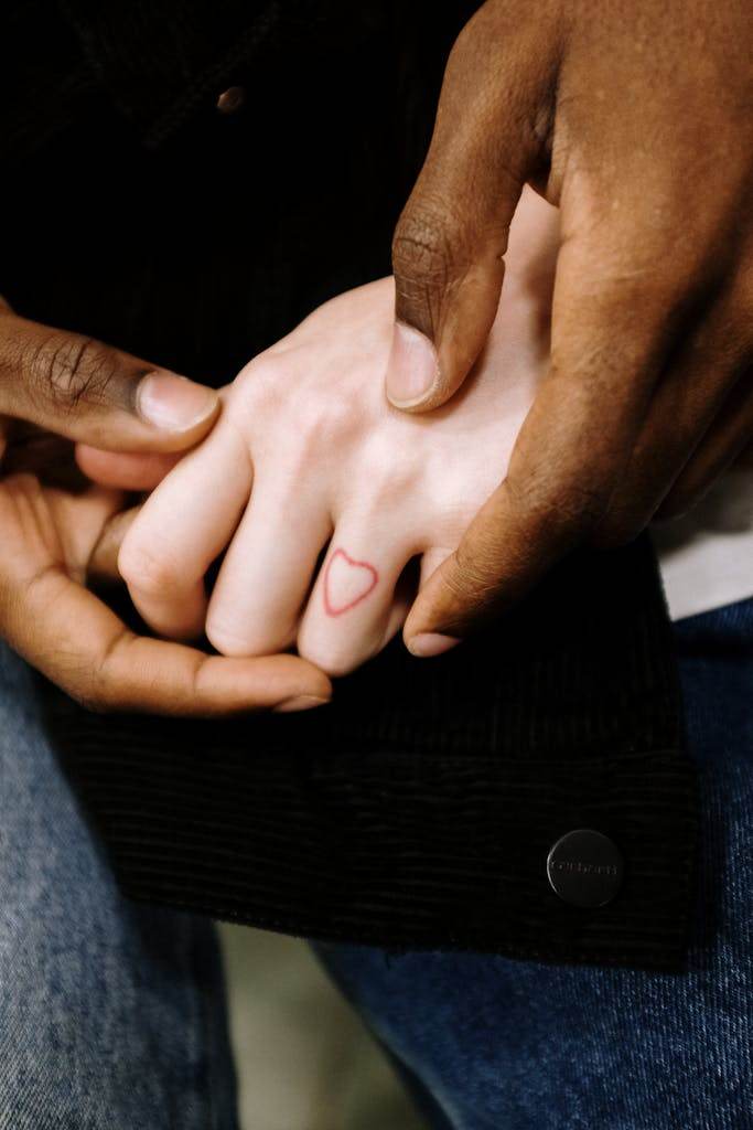 Tender moment of holding hands with a heart tattoo, symbolizing unity and affection.