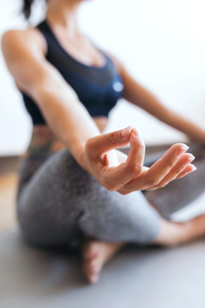 Woman practicing yoga in a seated meditation pose, focusing on her hand gesture.