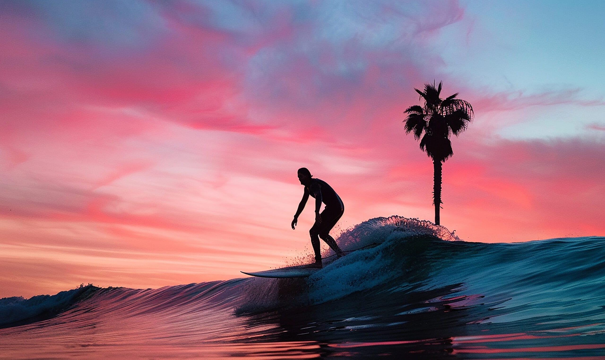 A surfer rides a wave at sunset, silhouetted against a colorful sky with a palm tree in the background.