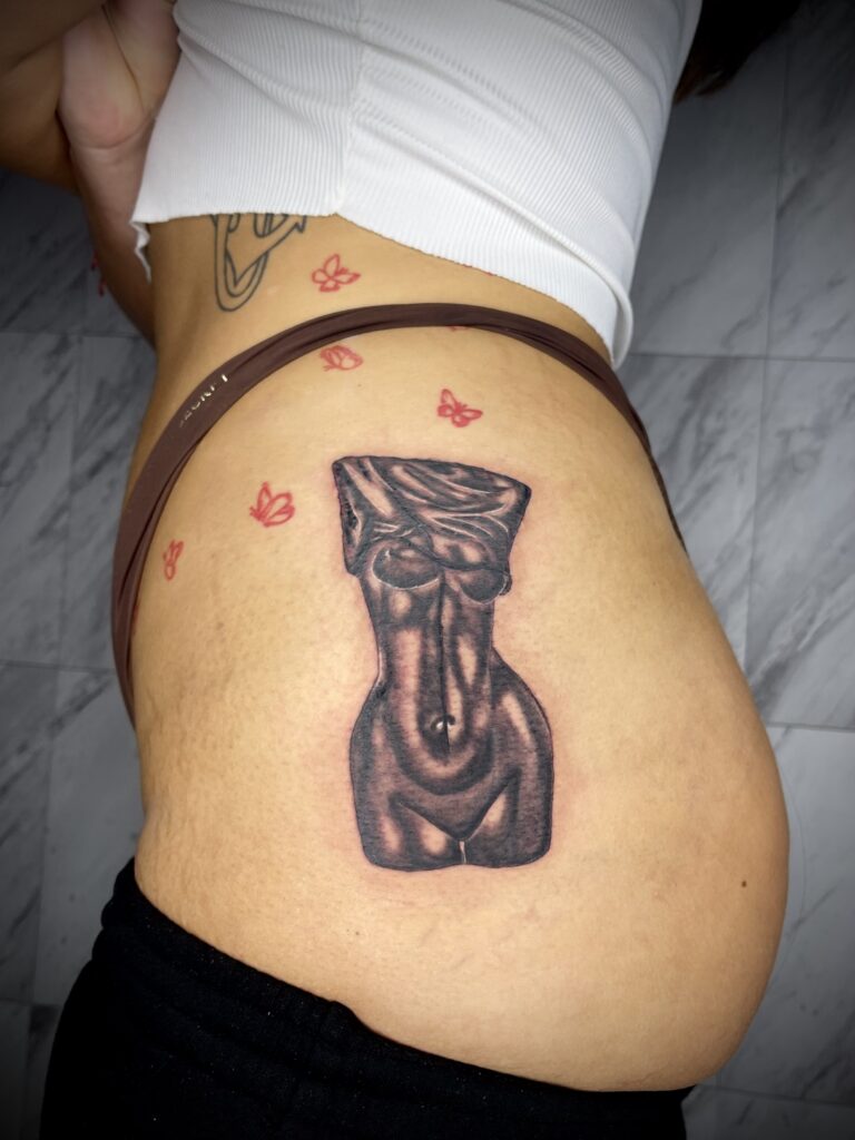 Tattoo of a stylized female torso with a cloth covering the head, surrounded by small red butterfly tattoos.