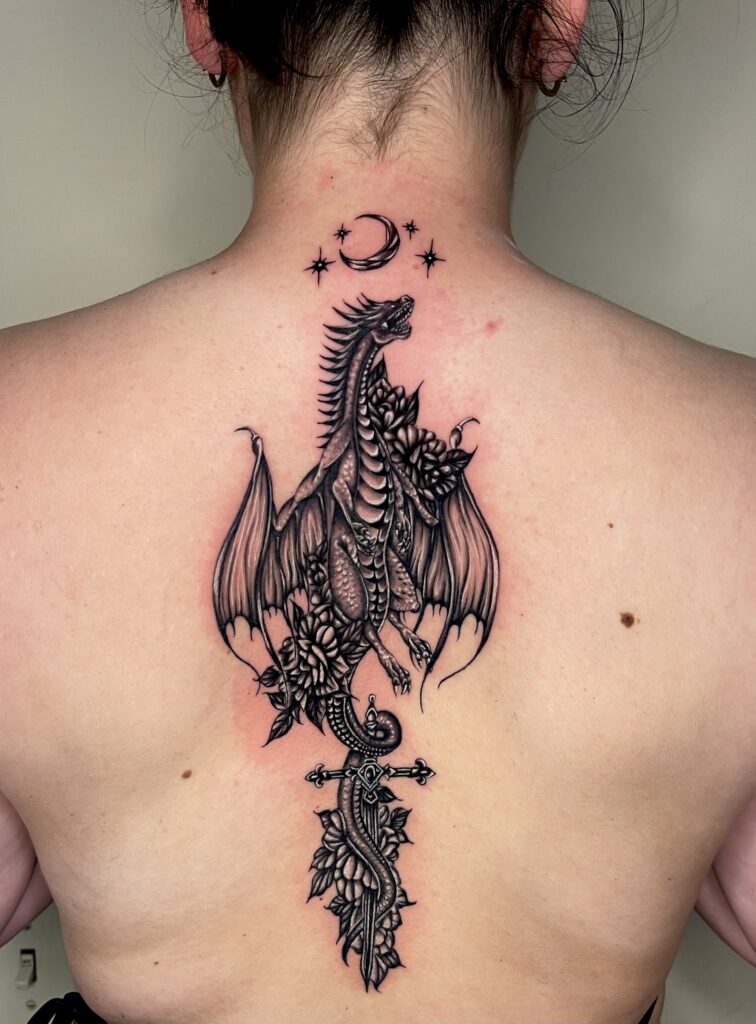 Black and gray dragon with wings, flowers, and a sword, under a crescent moon and stars.