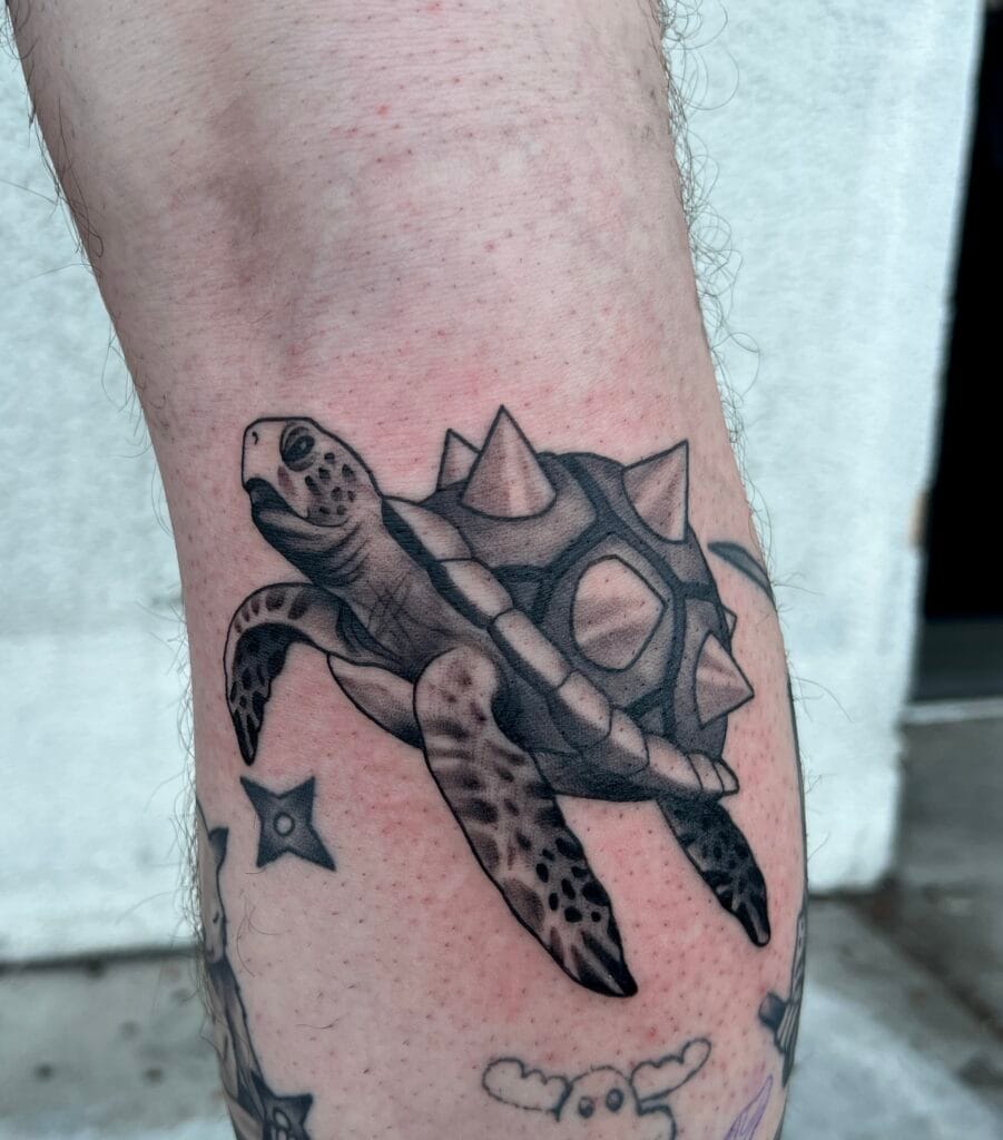 Black and gray tattoo of a turtle with a spiked shell on a persons arm.