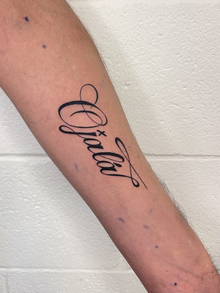 Black cursive tattoo of the name Orah on a persons forearm.
