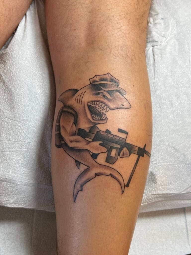 Shark with a human body wearing a cap, holding a sniper rifle, and standing on a crescent moon.