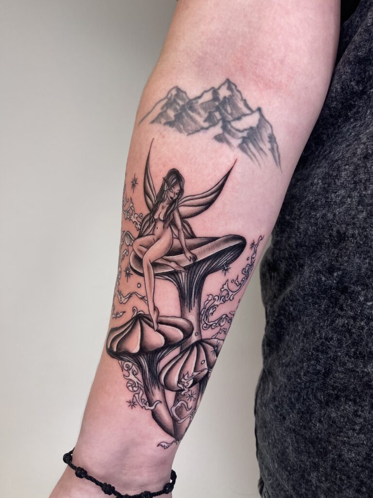 Fairy with wings sitting on a mushroom, with mountains in the background.