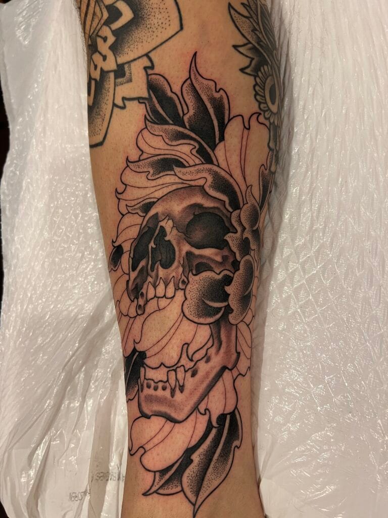 Black and gray skull with floral and leaf elements surrounding it.