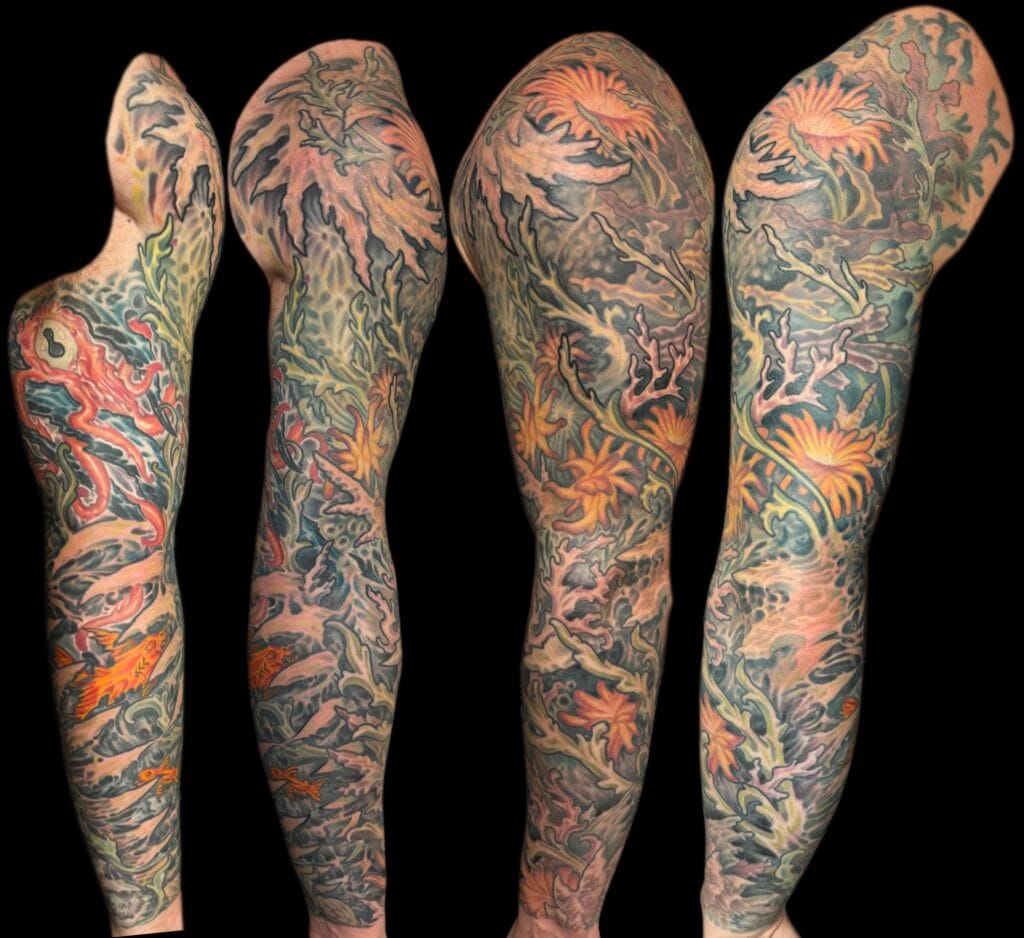 Full sleeve tattoos featuring colorful floral and oceanic designs on both arms.